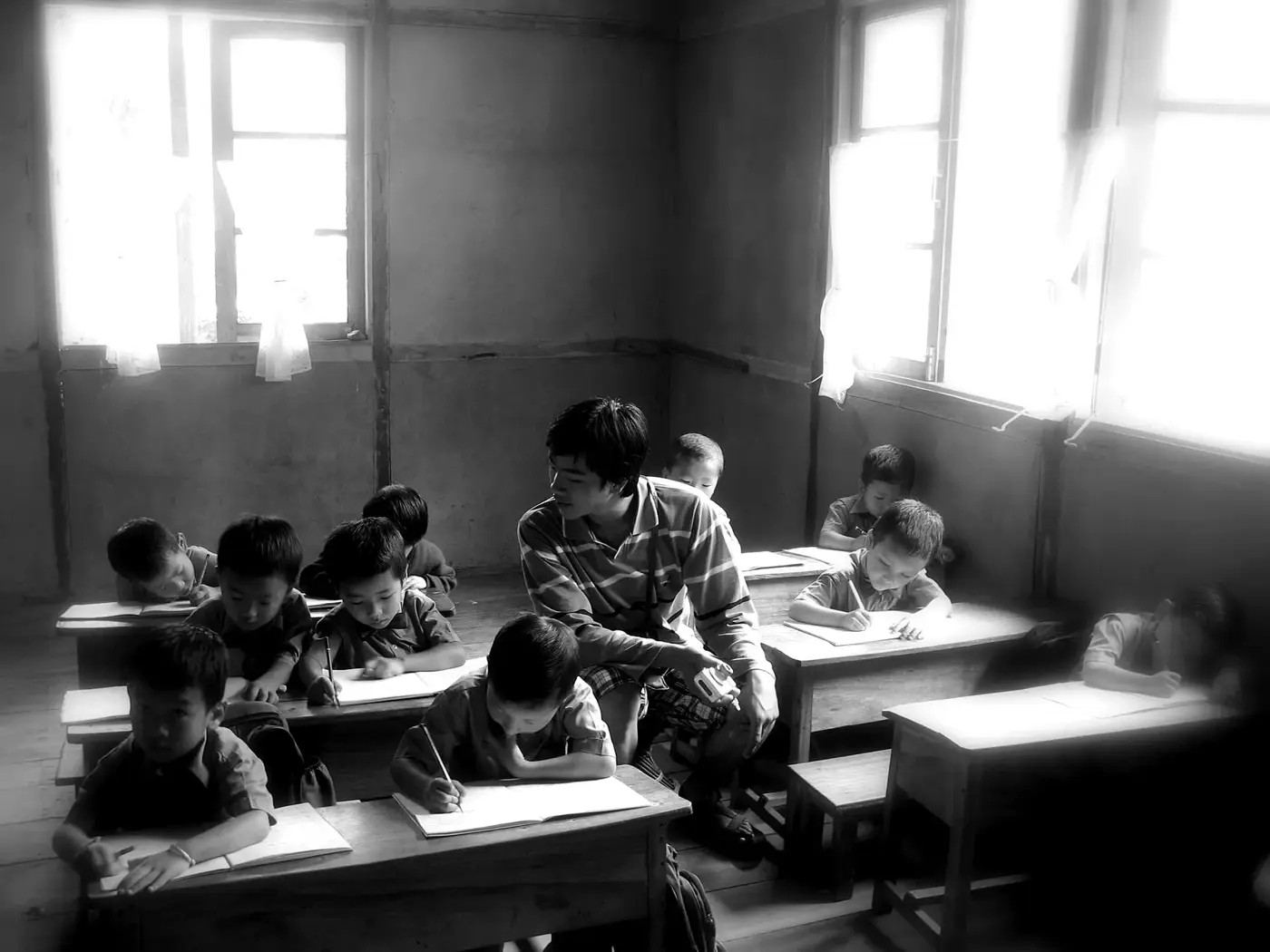 Students bent over their desks in a sunlit classroom in East Sikkim.