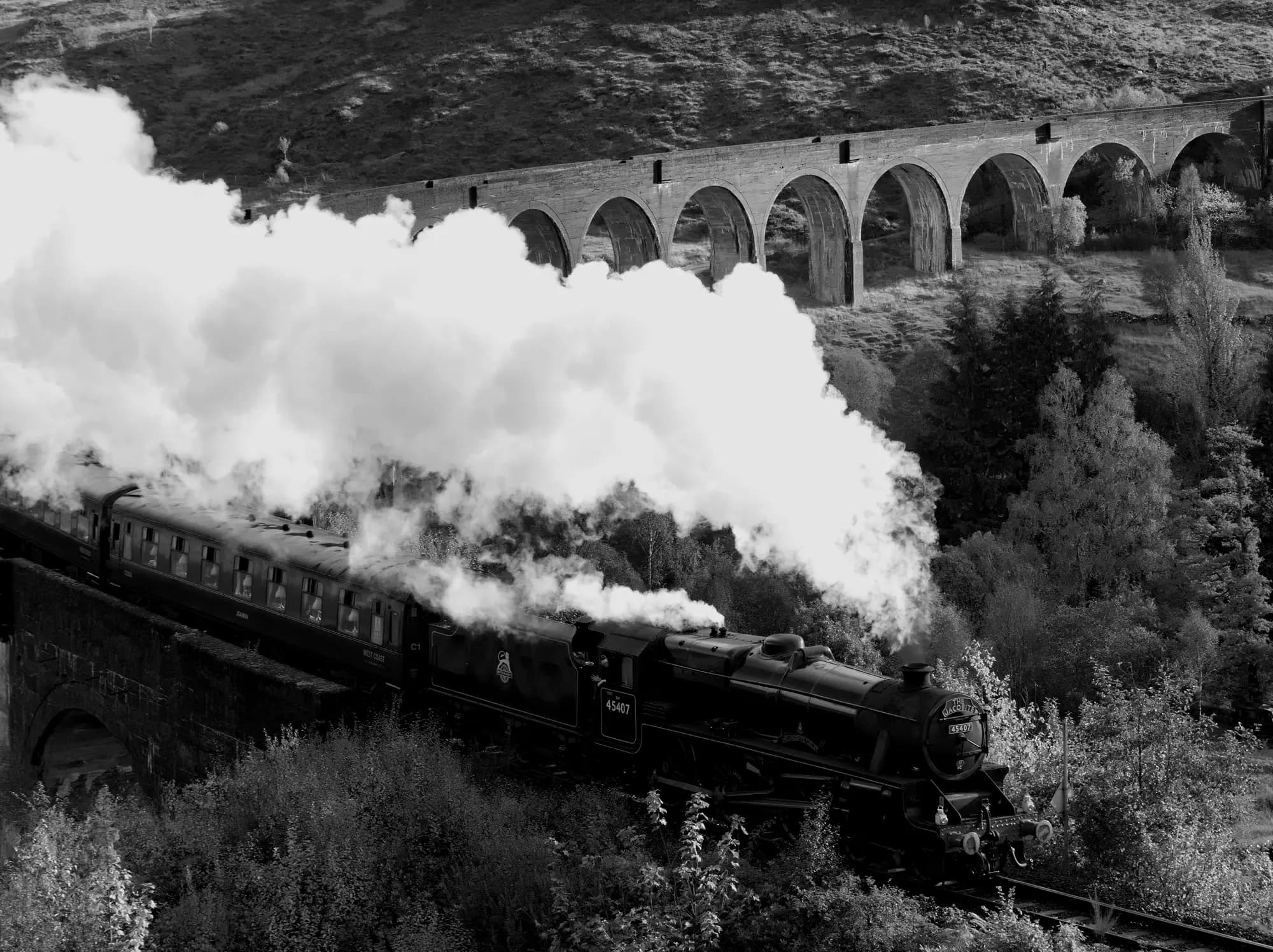 The Jacobite steam train on the Glenfinnan Viaduct, smoke trailing.